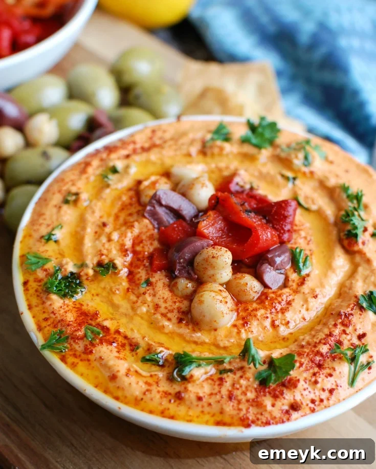 Roasted Red Pepper Greek Yogurt Hummus, a creamy and healthy dip, pairs beautifully with pita bread or fresh vegetables. It's packed with protein and delicious flavor.