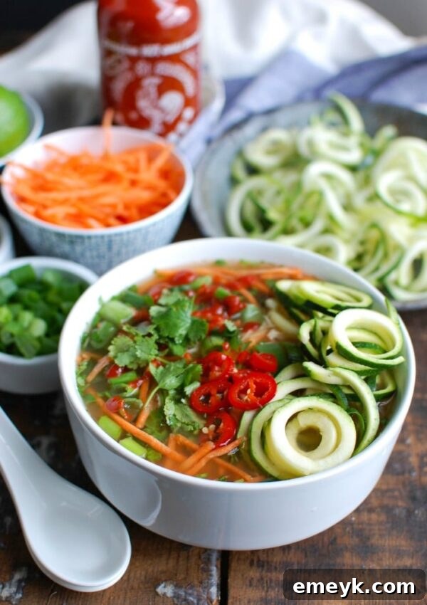 A vibrant bowl of Spicy Chicken Soup garnished with fresh cilantro and lime wedges, showcasing healthy zucchini noodles.