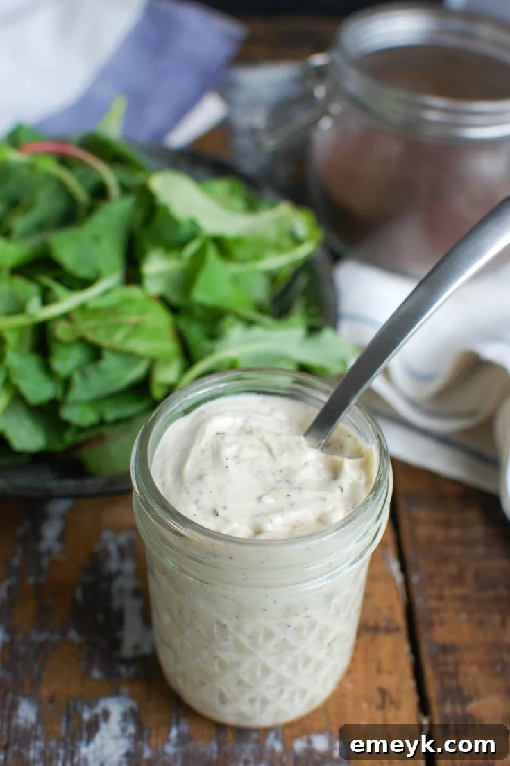 Spoon dipping into a jar of creamy Tahini Yogurt Dressing, highlighting its smooth texture.