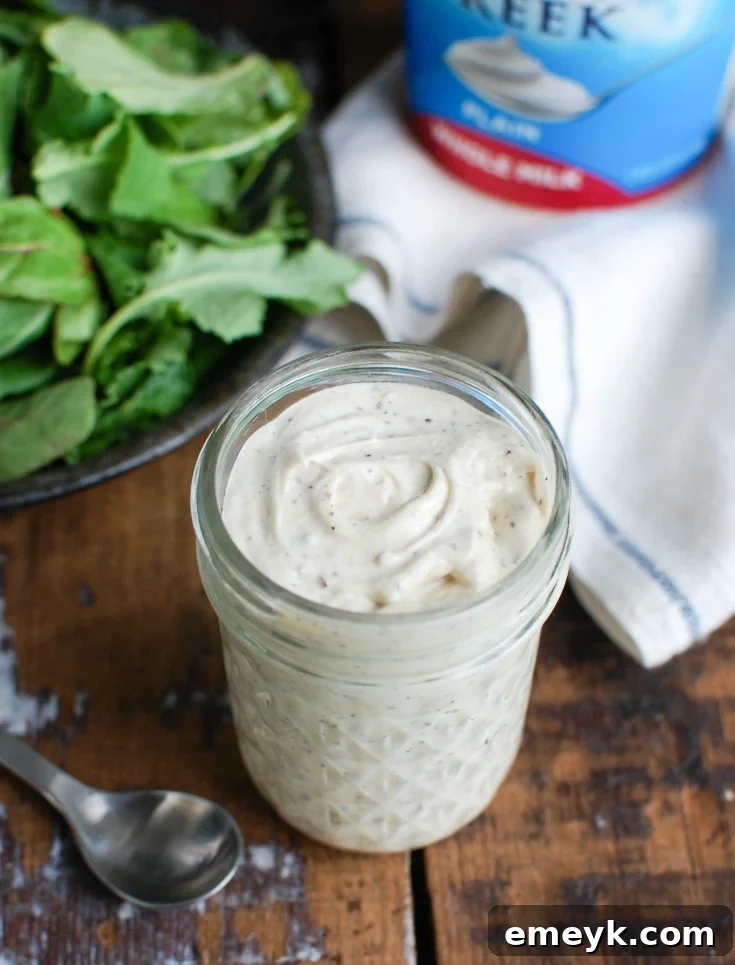 Tahini Yogurt Dressing in a jar next to a tub of yogurt, showing the key dairy ingredient.