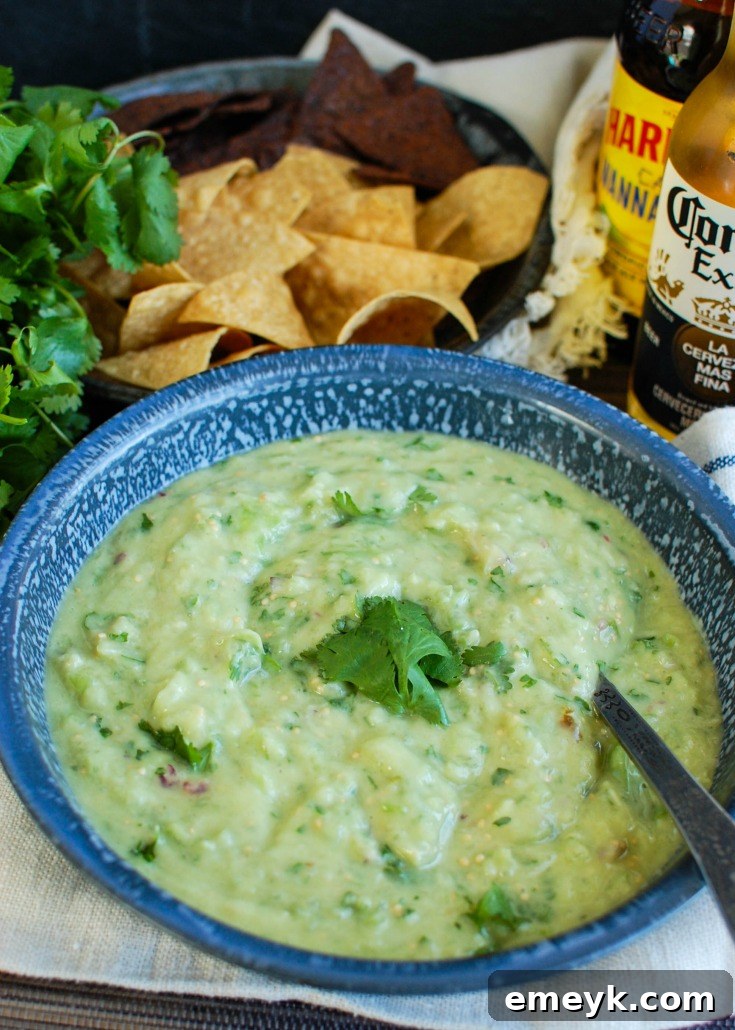 Avocado Tomatillo Salsa in a bowl with a spoon, showing its creamy texture.