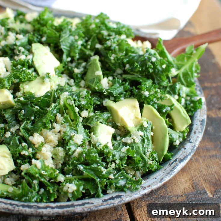 A top-down view of the Avocado Kale Quinoa Salad, showing the texture of cooked quinoa mixed with the soft, massaged kale, and neatly arranged avocado slices.