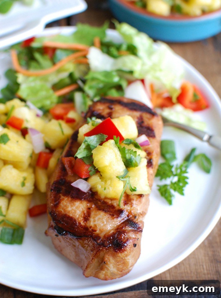 Aloha Grilled Pork Chops 3 A perfectly grilled Hawaiian Pork Chop on a white plate, cut open to show its juicy interior, with a fork ready to enjoy.