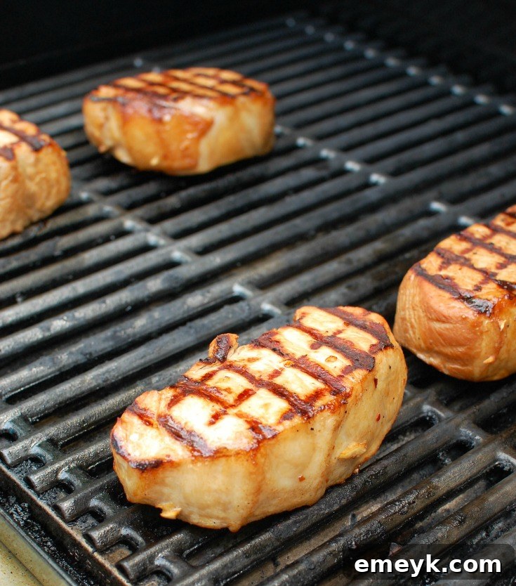 Aloha Grilled Pork Chops 4 Grilled Hawaiian Pork Chops cooking on a hot outdoor grill, showing the beautiful grill marks forming on the meat.