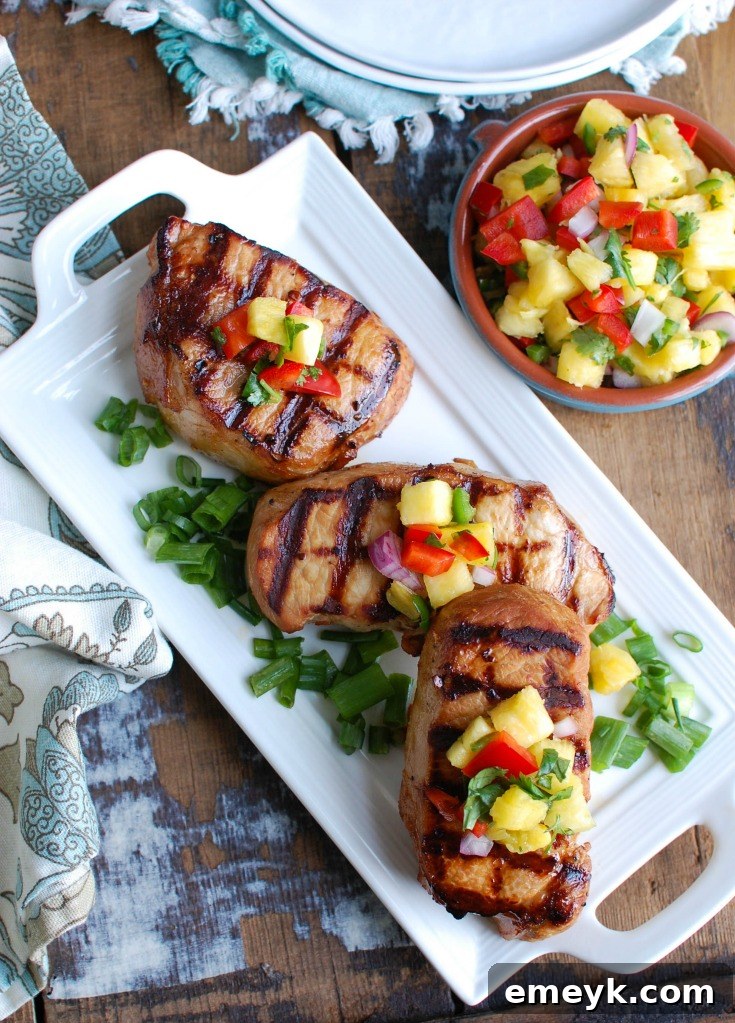 Aloha Grilled Pork Chops 6 A stack of perfectly grilled Hawaiian Pork Chops on a white plate with a patterned napkin, ready for a delicious meal.