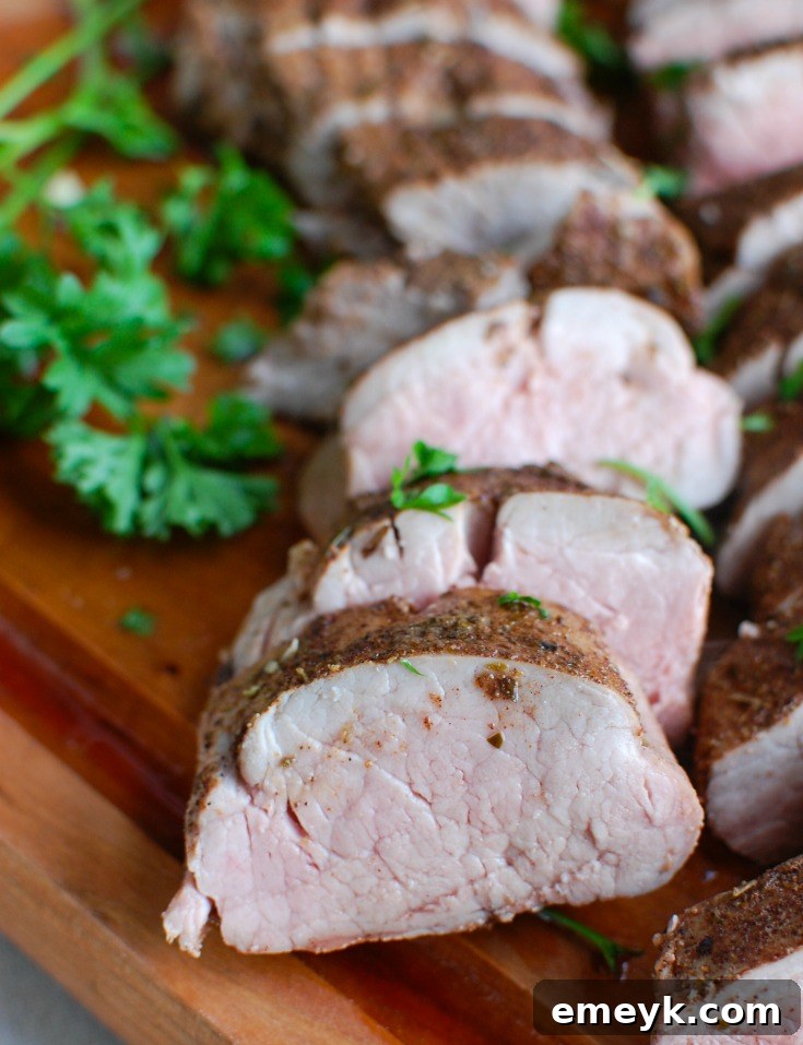 Raw pork tenderloin with garlic pieces inserted and Mediterranean spice rub applied.