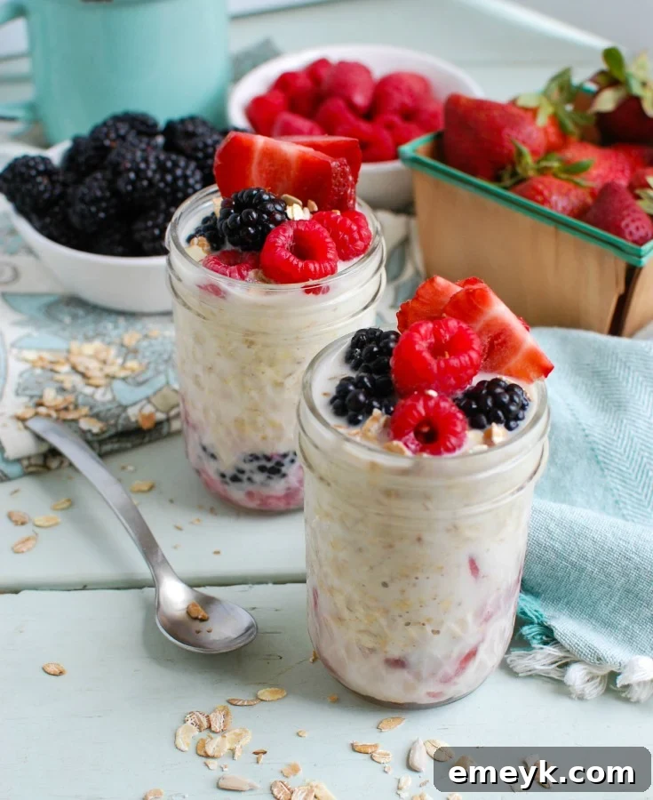 A mason jar filled with Overnight Triple Berry Oatmeal, garnished with a handful of fresh blueberries, raspberries, and sliced strawberries, along with a sprinkle of chia seeds, showcasing a vibrant and healthy breakfast.