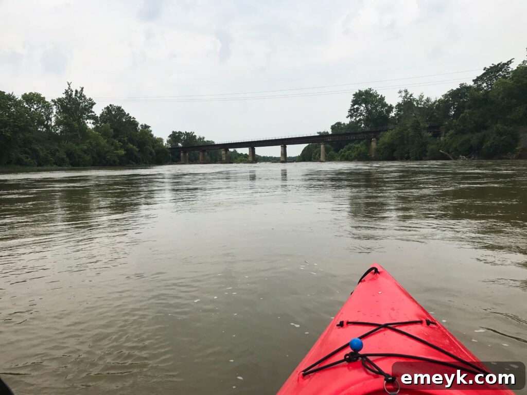 Kayakers enjoying a serene paddle on the Great Miami River, surrounded by lush greenery.