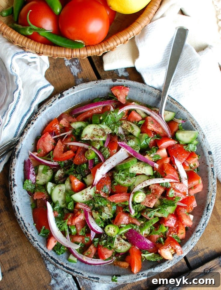 A close-up photo of Persian Tomato Cucumber Salad in a striking blue bowl, garnished with fresh mint leaves, showcasing its appetizing appeal.