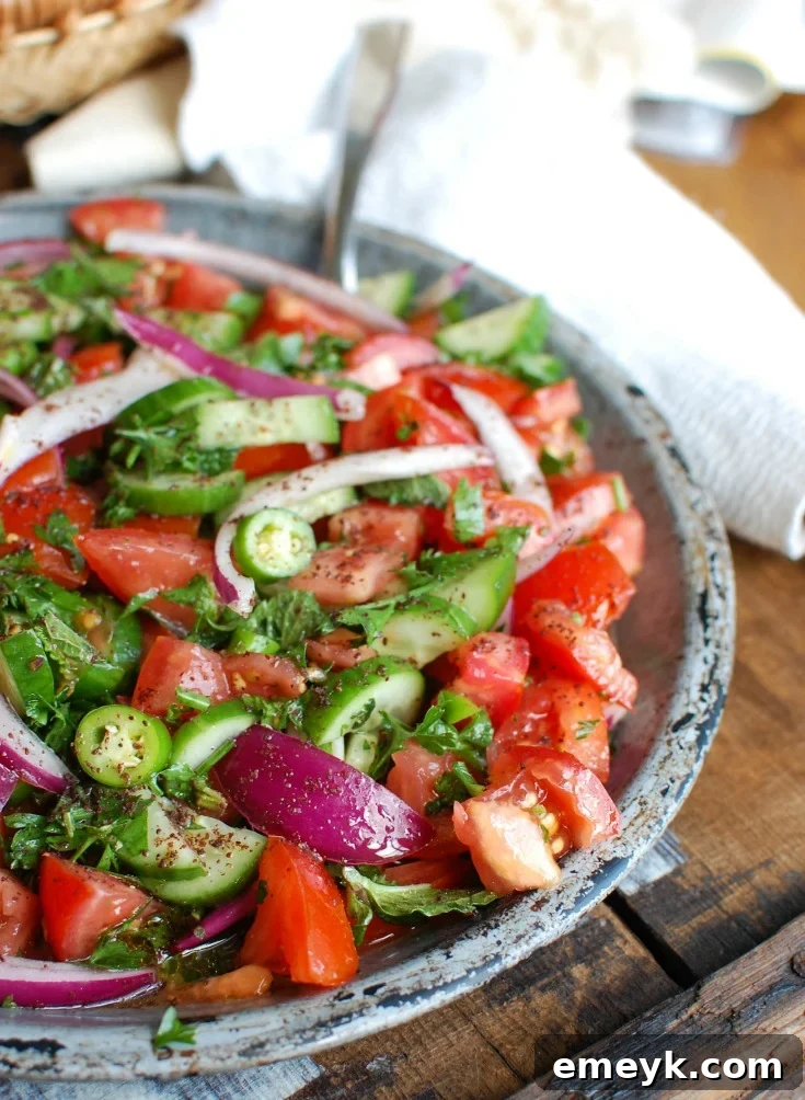A side view of the Persian Tomato Cucumber Salad in a bowl, showing the texture and vibrant colors of the ingredients.