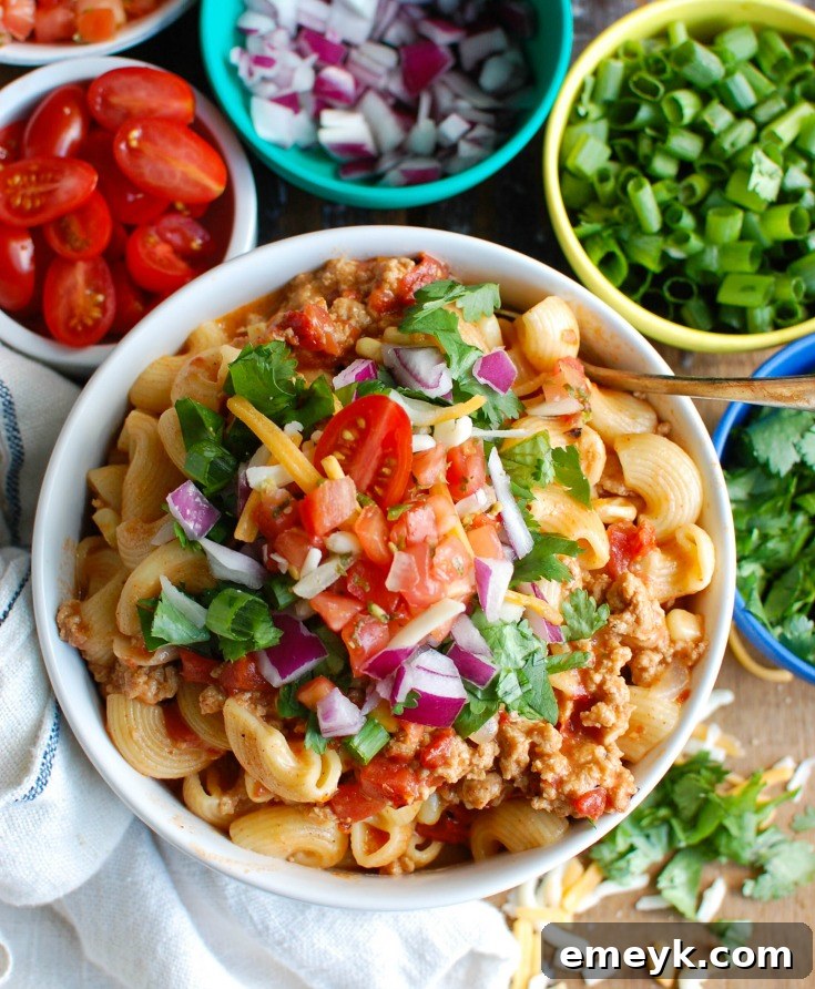 A serving of Instant Pot Turkey Taco Pasta garnished with extra cheese, diced tomatoes, and a sprinkle of herbs.
