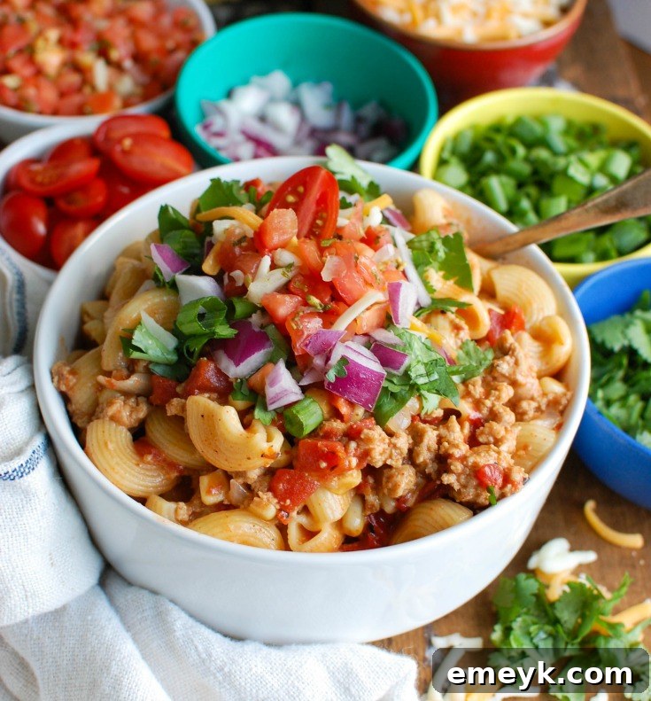 Instant Pot Turkey Taco Pasta in a white bowl, garnished with cherry tomatoes and green herbs.