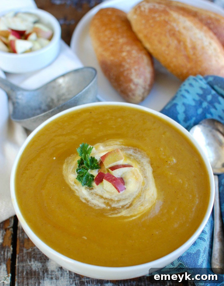 Slow Cooker Butternut Squash Apple Soup garnished with parsley and a drizzle of cream.