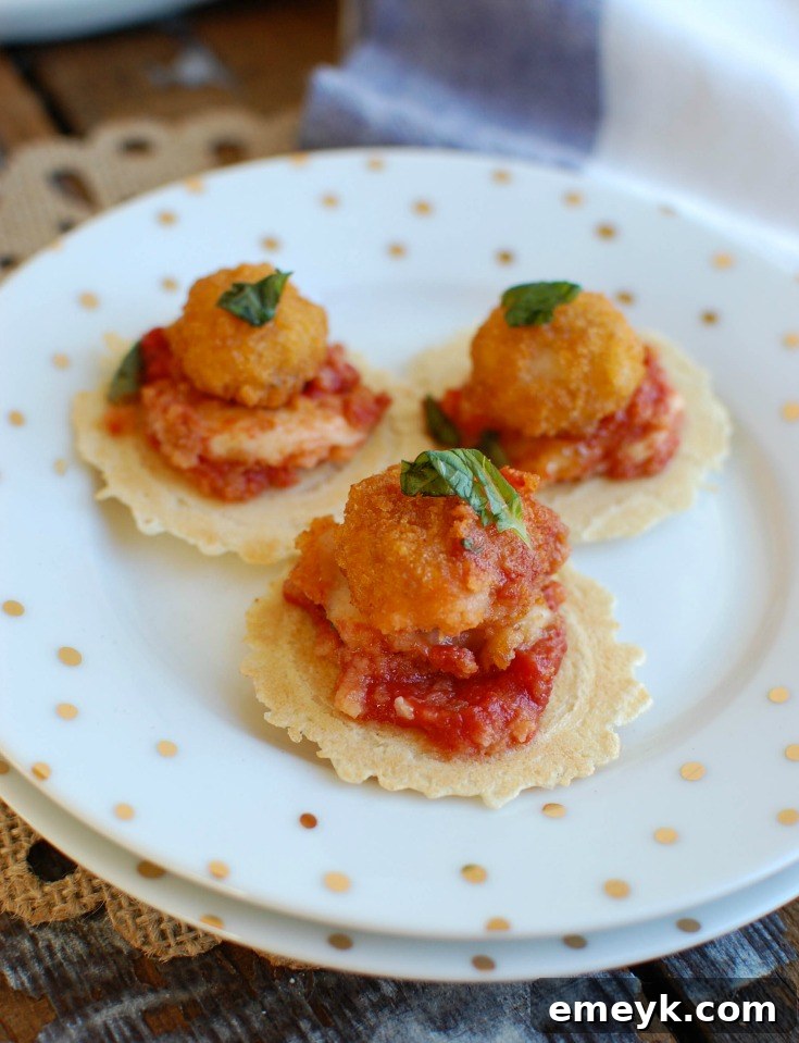 Close-up of freshly baked Tomato Basil Mozzarella Popcorn Shrimp Bites in a skillet, showcasing the melted mozzarella, bright red tomato sauce, and green basil on top of golden popcorn shrimp, ready to be served with crackers or crusty bread.