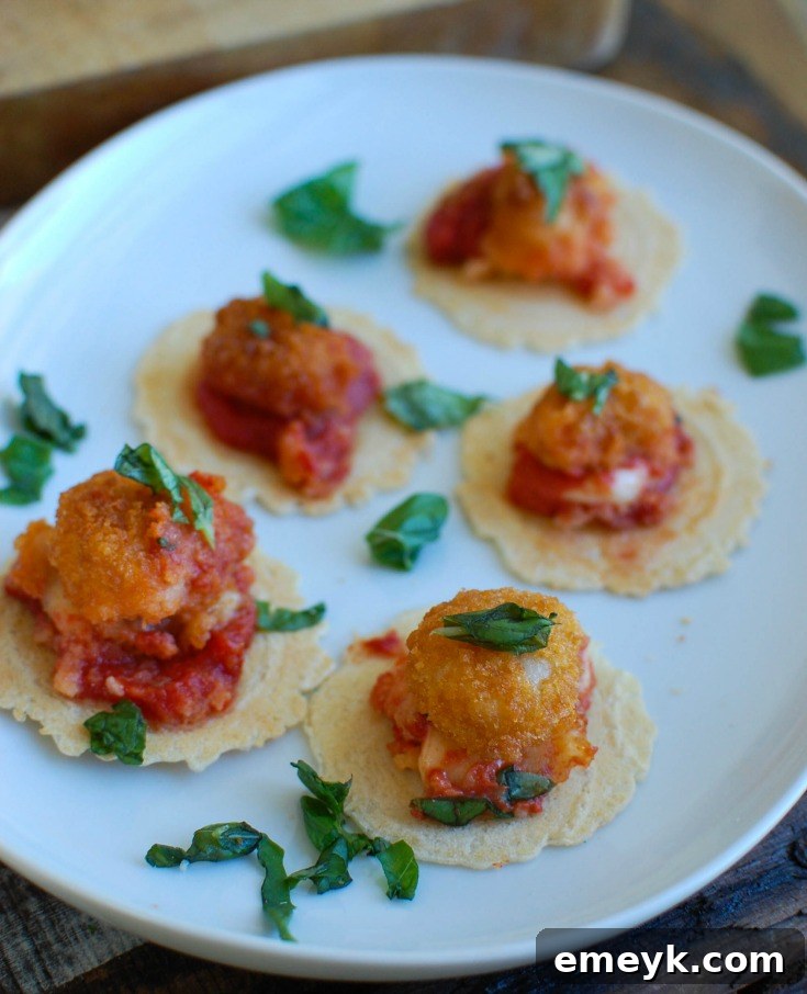 A top-down view of a cast iron skillet filled with Tomato Basil Mozzarella Popcorn Shrimp Bites, showing the golden-brown shrimp nestled in a rich tomato sauce with melted mozzarella and fresh basil leaves, ready for serving.