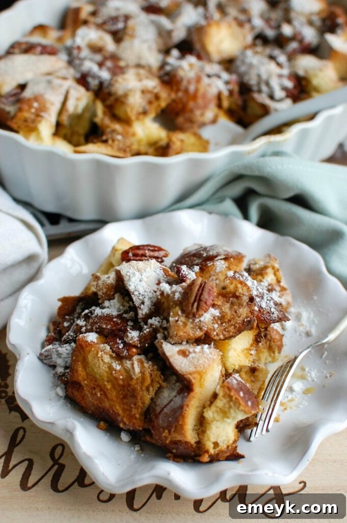 A serving of Overnight Gingerbread French Toast Casserole on a plate, topped with powdered sugar and pecans, ready to be enjoyed.