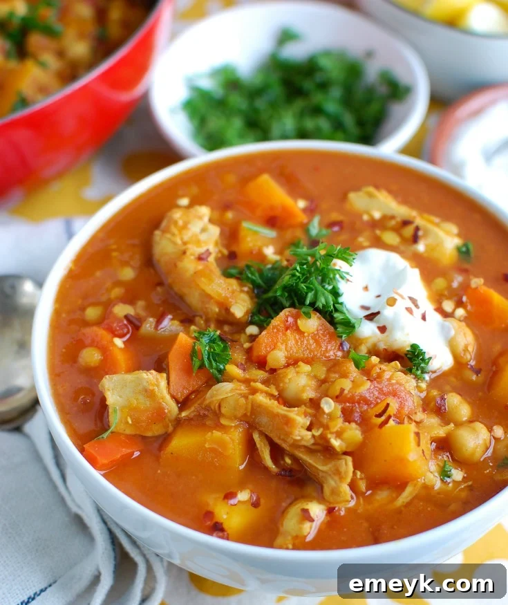 A steaming bowl of Slow Cooker Moroccan Chicken Soup garnished with fresh herbs and a dollop of Greek yogurt.