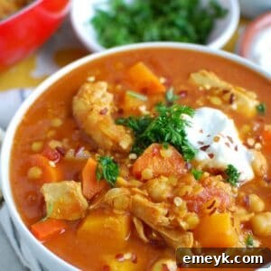 Slow Cooker Moroccan Chicken Soup in a white bowl, garnished with fresh herbs.