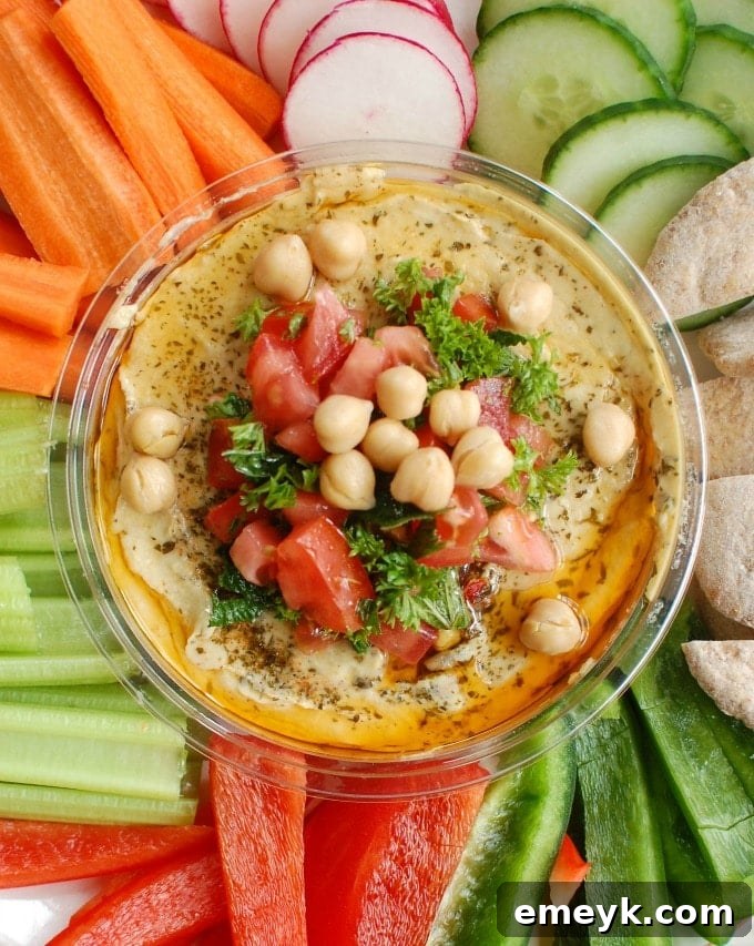 Creamy hummus is topped with diced tomatoes, fresh parsley and mint, chickpeas, pine nuts and a squeeze of lemon juice. Serve this with a rainbow of vegetables and whole wheat pita.