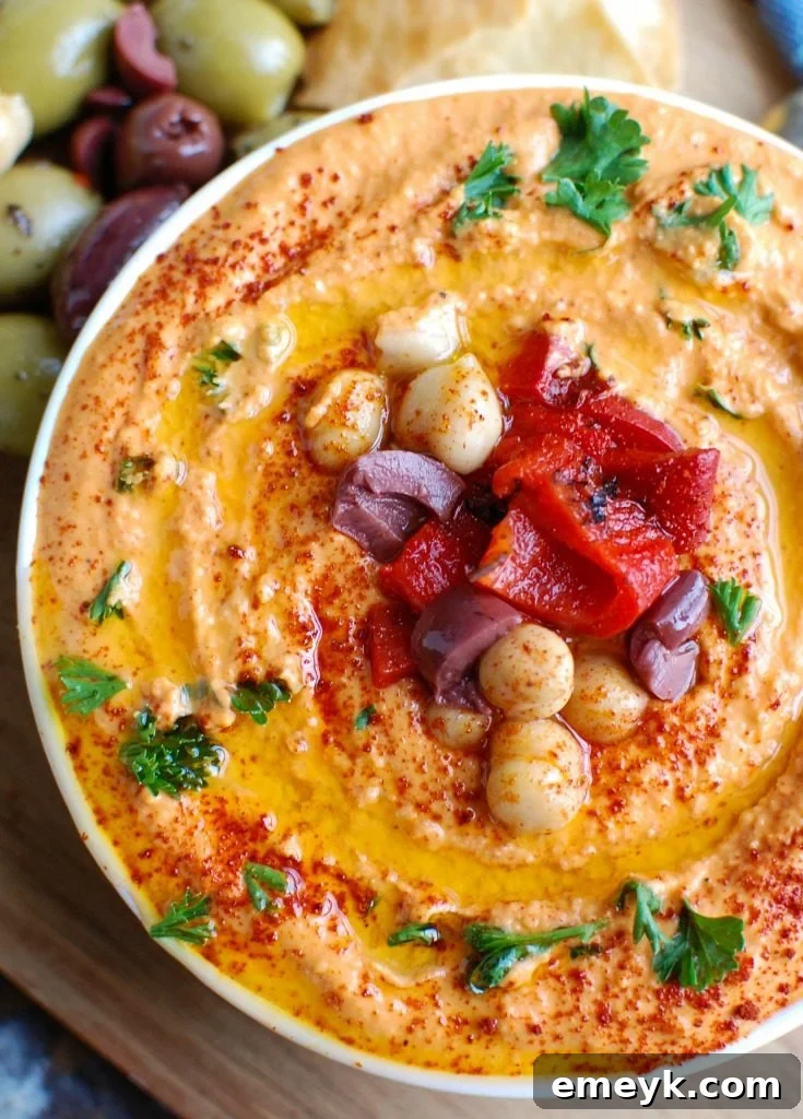 Roasted Red Pepper Greek Yogurt Hummus is a creamy dip that pairs nicely with pita bread or fresh vegetables. Chickpeas, tahini, lemon juice, spices and fire roasted red peppers are blended with Greek yogurt for added protein and creaminess making this not only healthy, but delicious! 