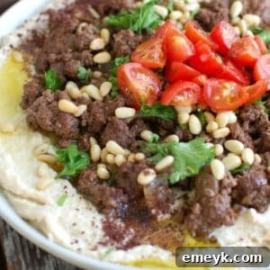 Hummus with Spiced Beef and Toasted Pine Nuts on white plate, ready to be served.
