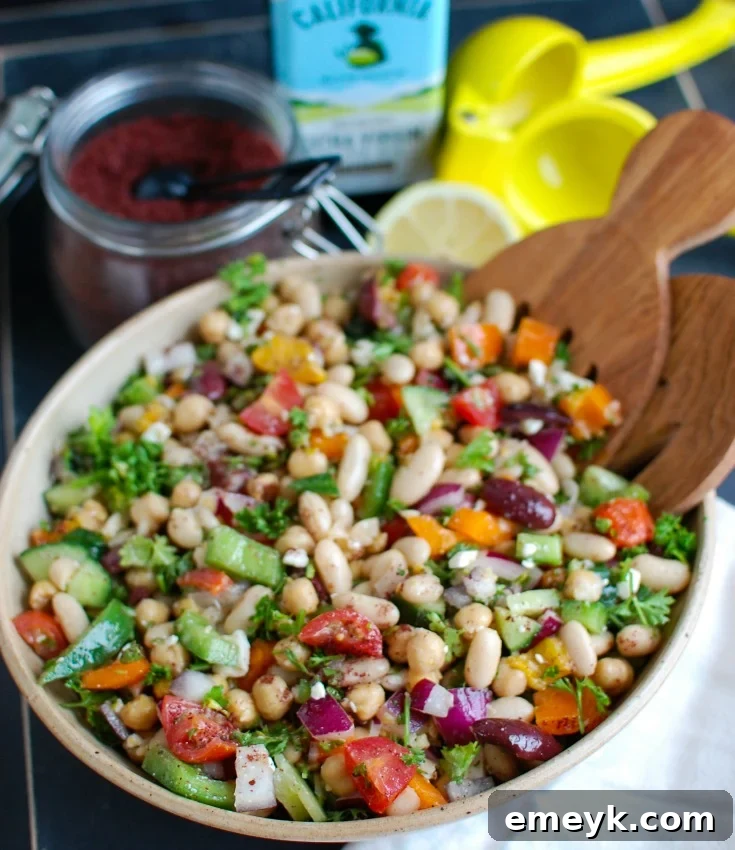 Mediterranean Bean Salad in a bowl with a slice of lemon and fresh mint for garnish.