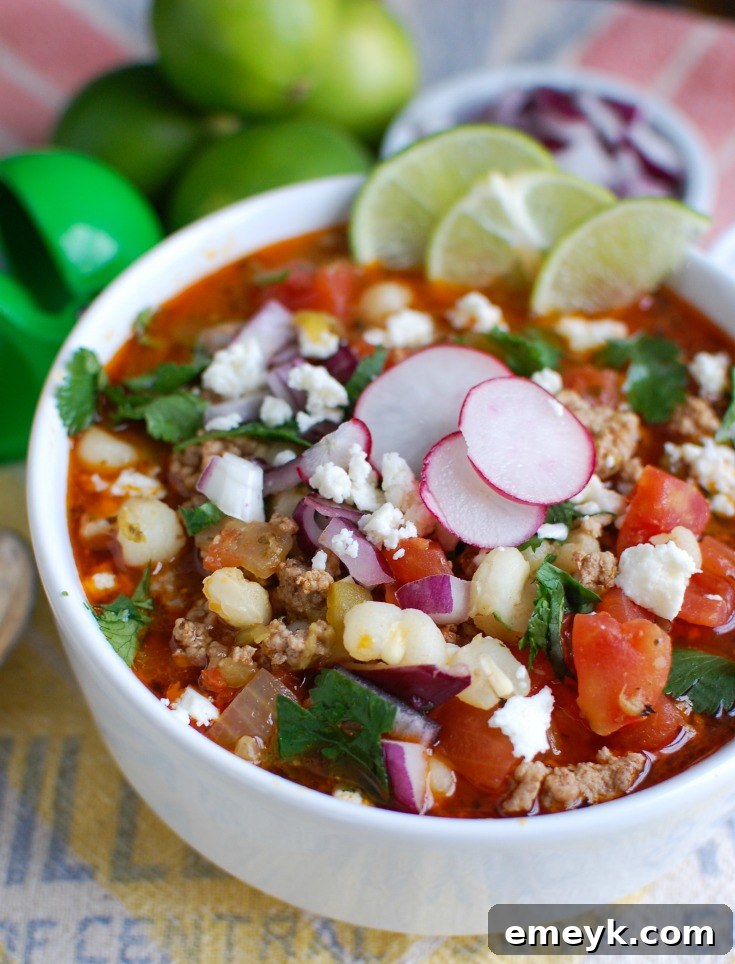 A steaming bowl of Slow Cooker Pork Pozole, garnished with fresh cilantro and vibrant radishes, served in a pristine white bowl.