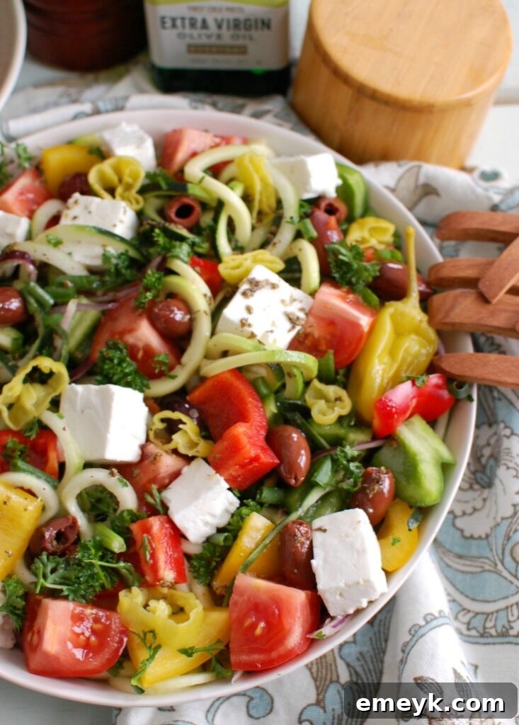 Spiralized Greek Style Salad being served with wooden tongs