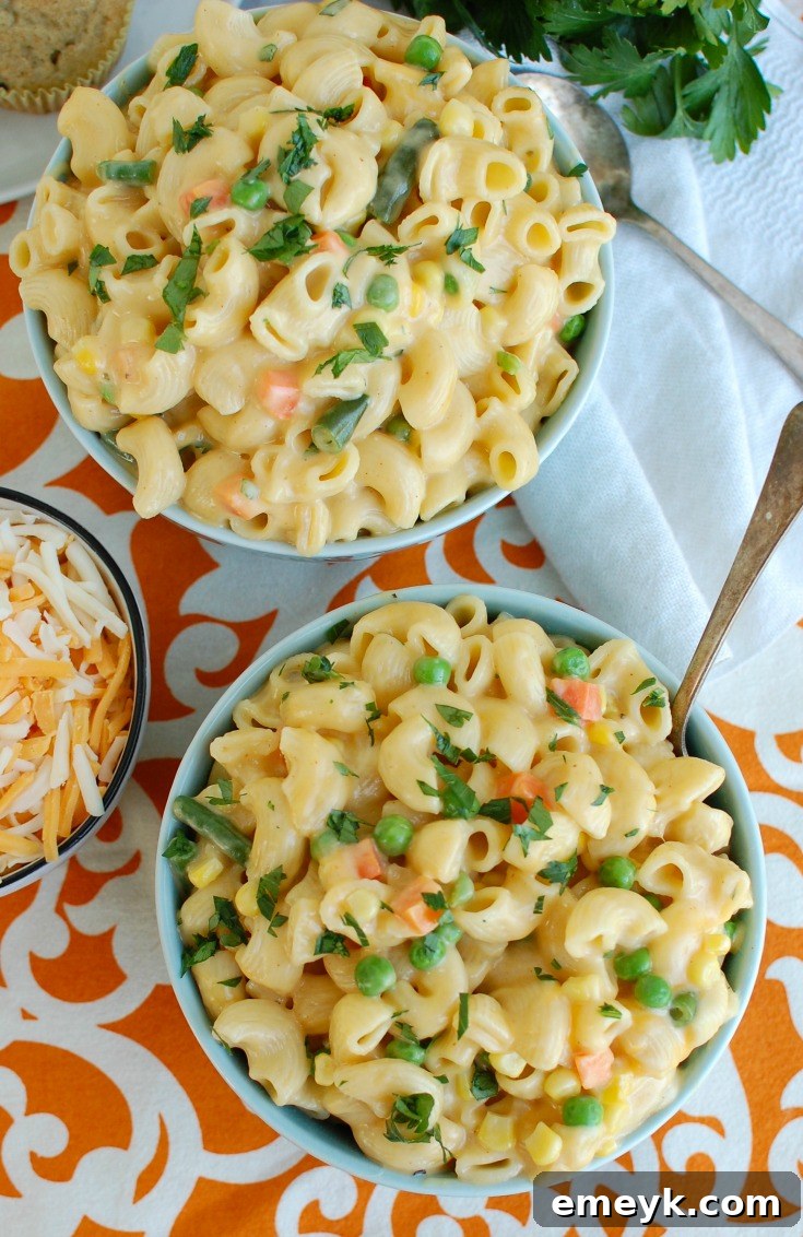 Two bowls of Instant Pot Vegetable Mac and Cheese, showcasing the vibrant colors of the vegetables and the rich cheese sauce.