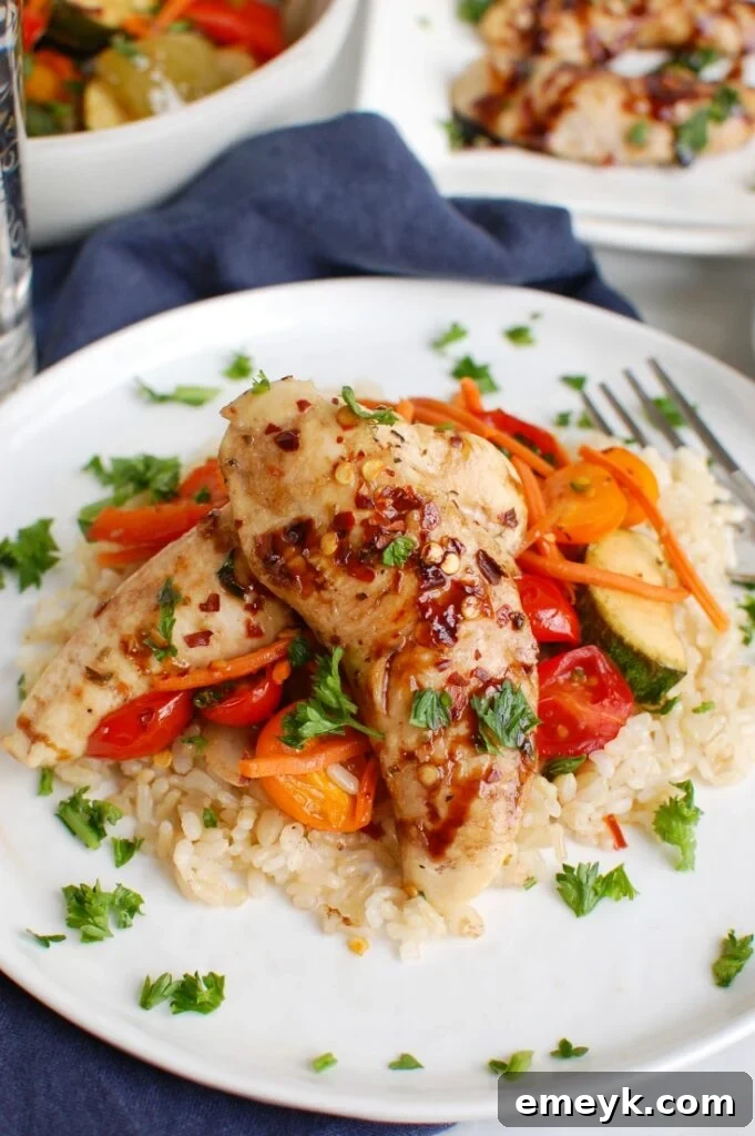 Sheet Pan Honey Balsamic Chicken Tenders and Vegetables served on a white plate, garnished with fresh herbs.