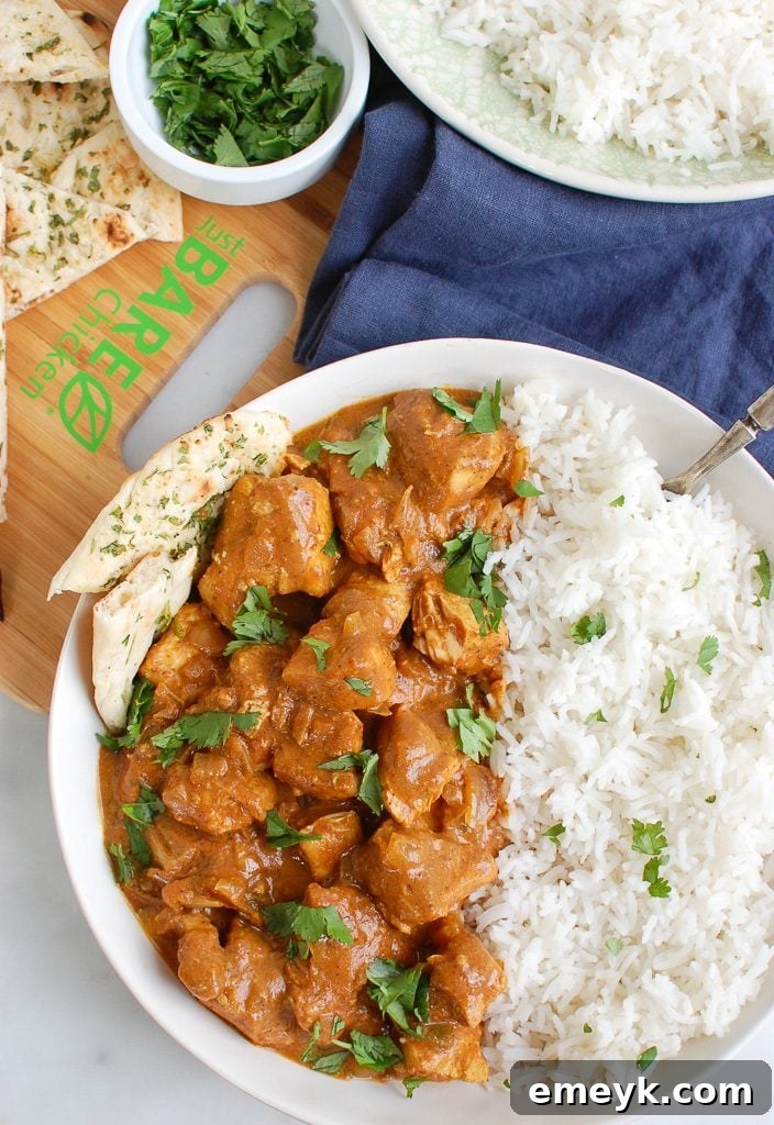 Slow Cooker Butter Chicken served in a bowl, garnished with cilantro, with naan bread on the side.