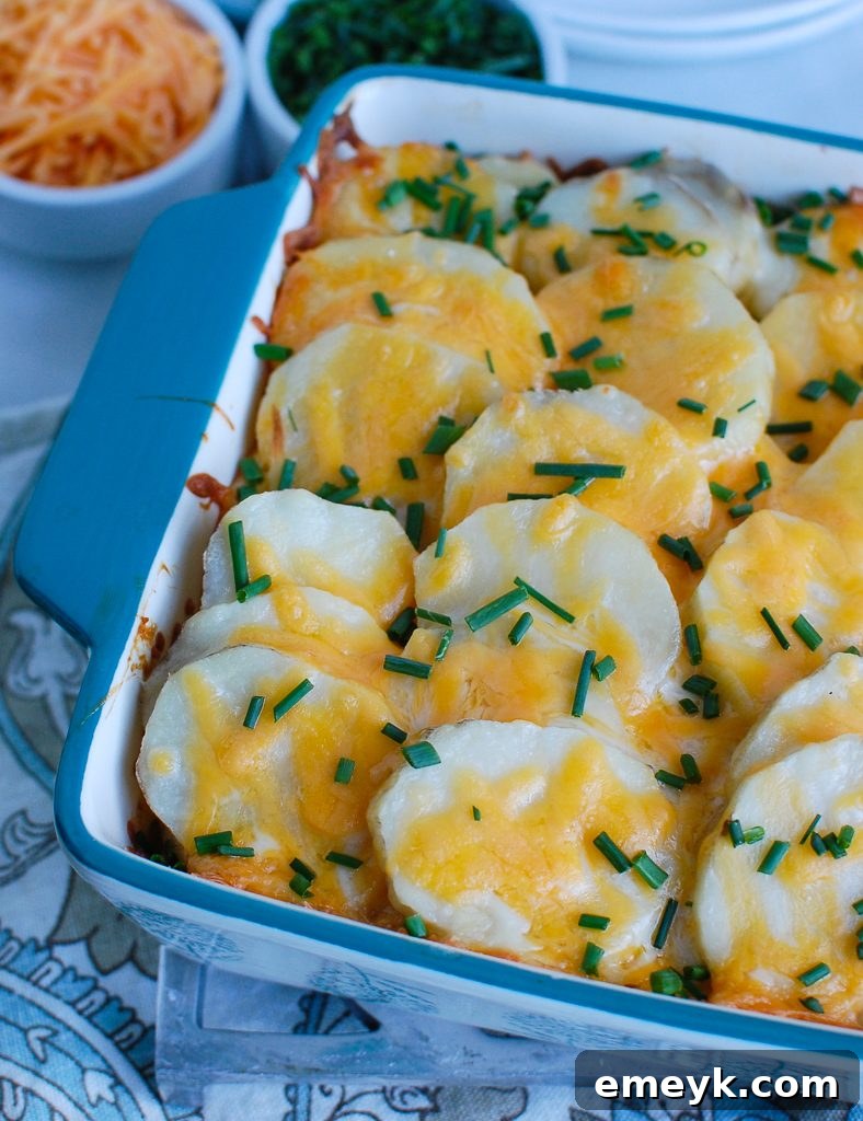 The golden-brown, bubbly top of Spinach Artichoke Scalloped Potatoes in a blue baking dish, fresh from the oven.