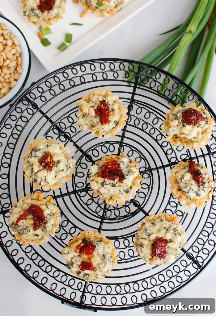 Overhead shot of freshly baked Spinach Artichoke Sun-dried Tomato Phyllo Bites on a wire rack, showcasing their golden crispness.