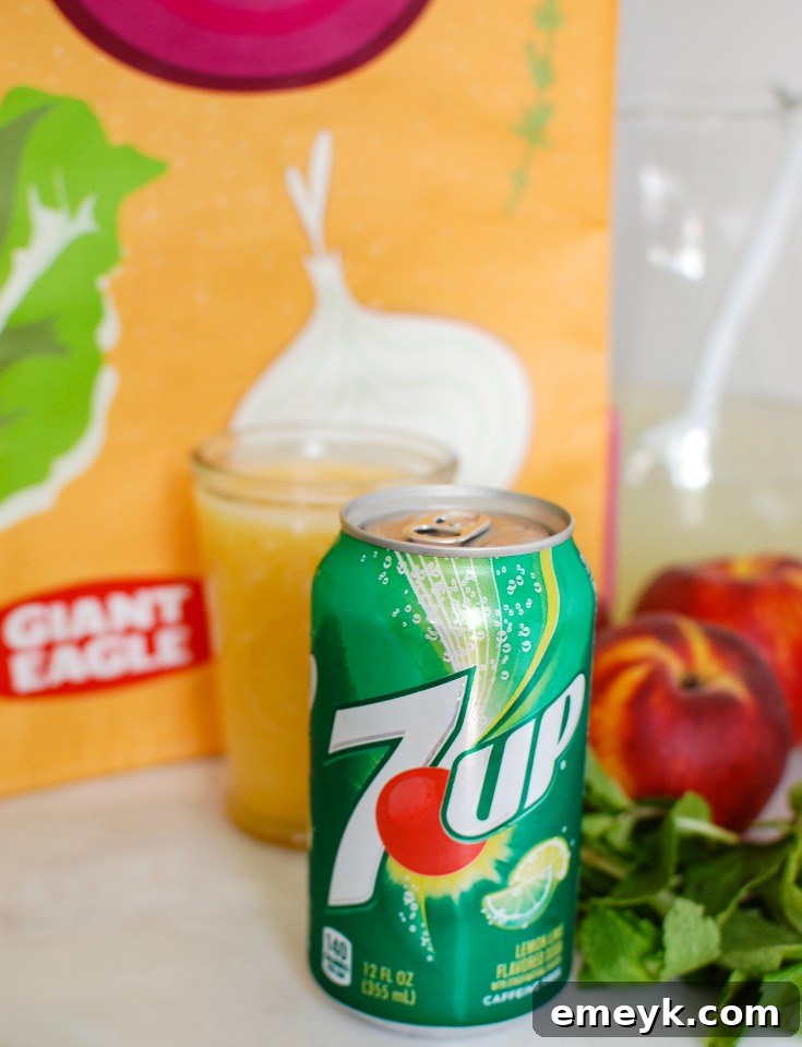 Ingredients for Sparkling Peach Lemonade laid out, including fresh peaches, lemonade concentrate, 7UP, and mint