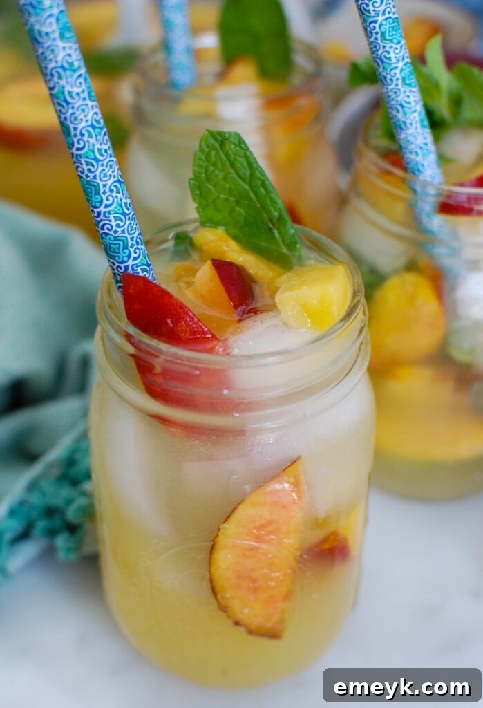 Close-up view of Sparkling Peach Lemonade in a glass, highlighting the peach slices and mint