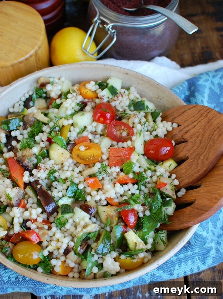 Side view of a vibrant Mediterranean Grilled Vegetable Couscous Salad in a white bowl, garnished with fresh herbs.