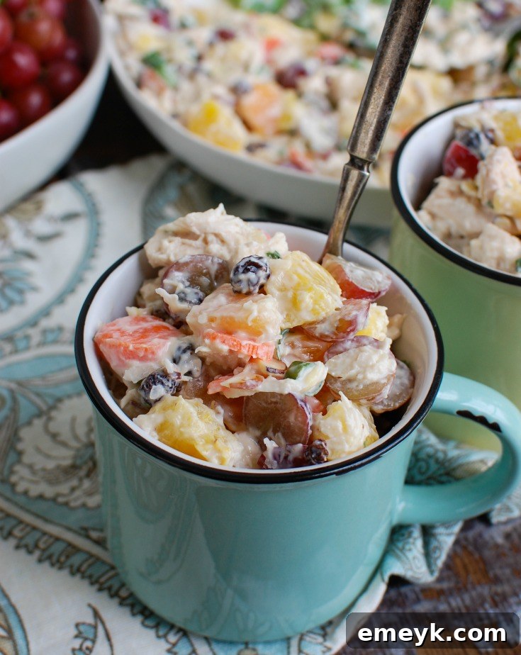 Island Escape Chicken Salad 3 Close-up of Tropical Chicken Salad served in a clear glass cup, showcasing the vibrant colors of pineapple, grapes, and mandarins against the chicken.
