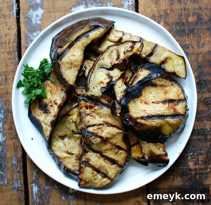 Close-up of Mediterranean Eggplant Salad on a white plate, highlighting grilled eggplant slices and fresh herbs