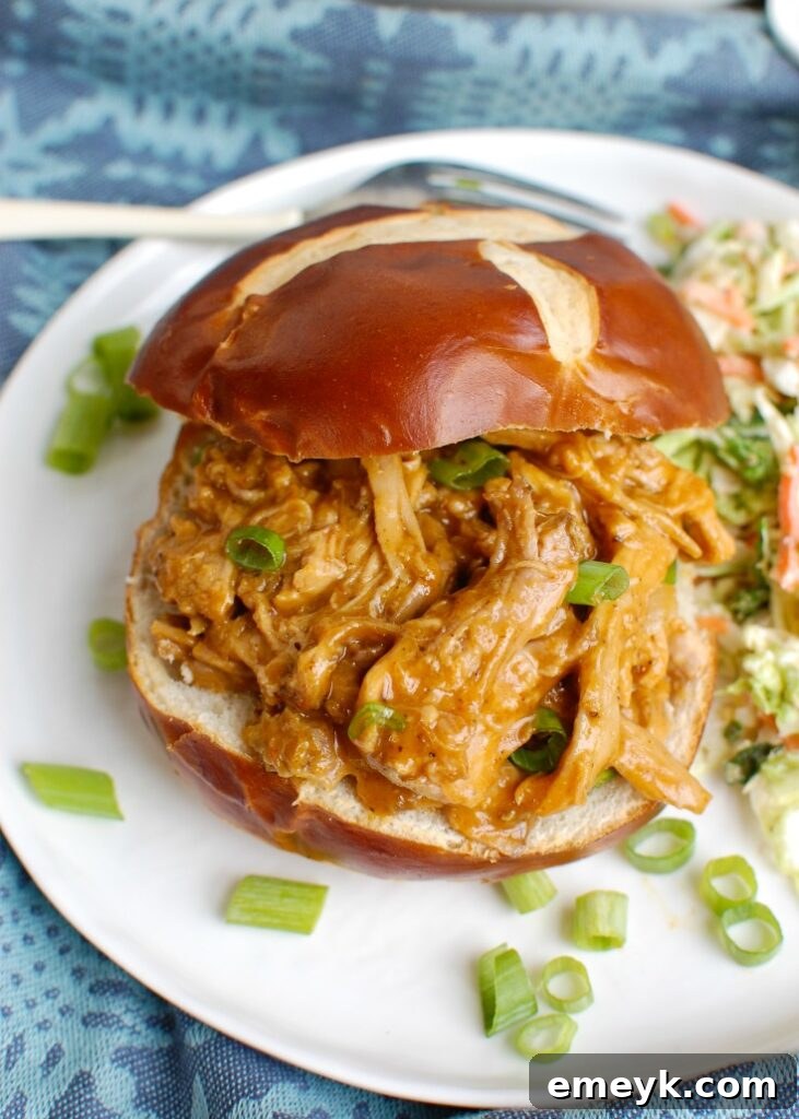 Delicious Slow Cooker Pork Tenderloin Sandwich served on a bun with fresh garnish.