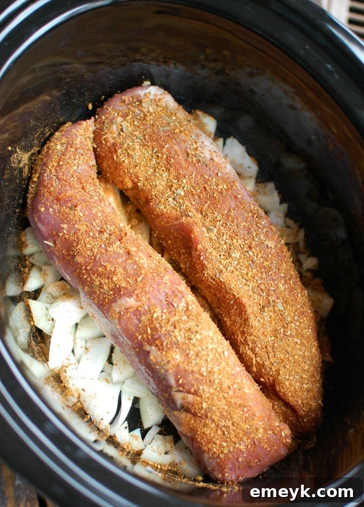 Two pork tenderloins in a slow cooker, ready for cooking.