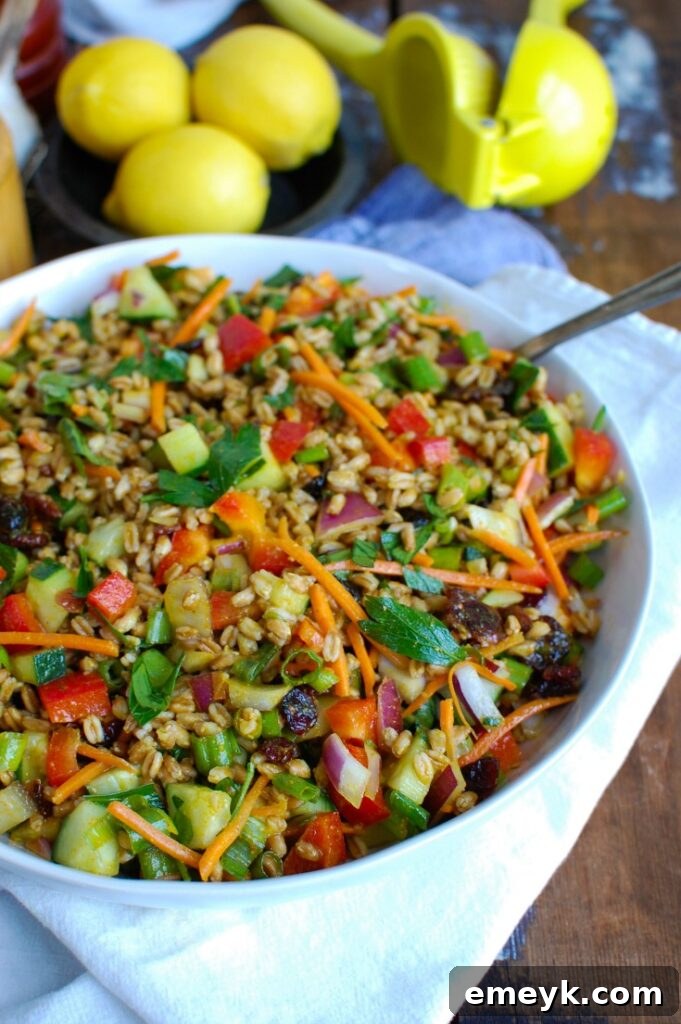 Refreshing Summer Farro Bowl 5 Serving of Easy Summer Farro Salad in a white bowl with a wooden spoon