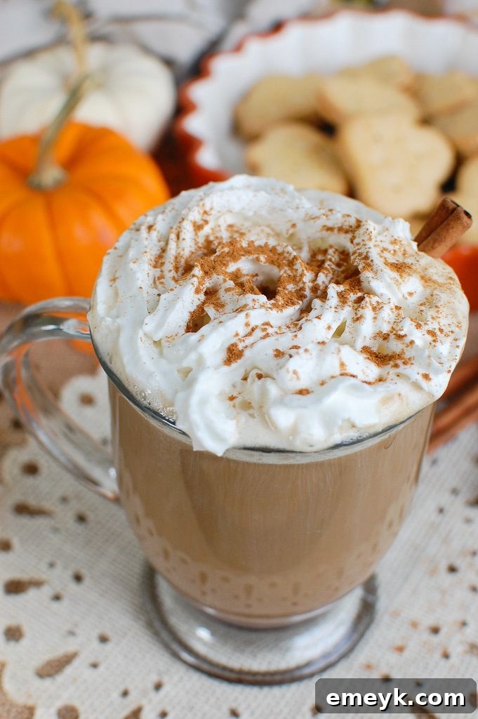 Fall's Signature Sip 2 Close-up of a steaming homemade Pumpkin Spice Latte, topped with whipped cream and a sprinkle of pumpkin pie spice, in a cozy fall setting.