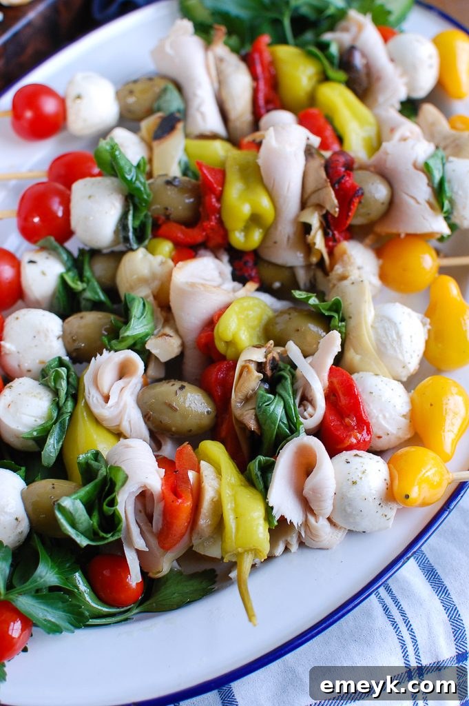 Sunny Mediterranean Skewers 3 Close-up of Mediterranean Antipasto Skewers featuring deli turkey breasts, olives, and fresh mozzarella balls, arranged on a white serving plate