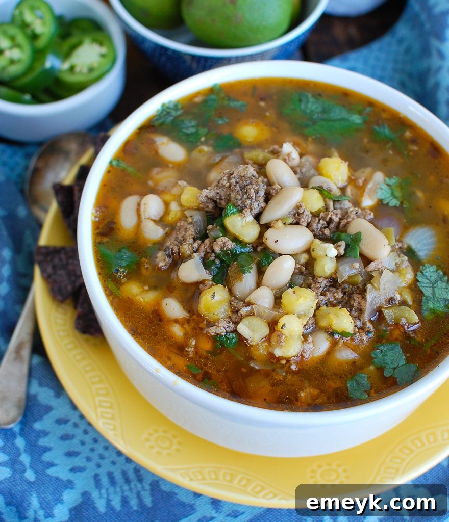 Zesty Instant Pot Pork Verde 4 A serving of Instant Pot Pork Chili Verde in a white bowl, with a small piece of cornbread on the side.