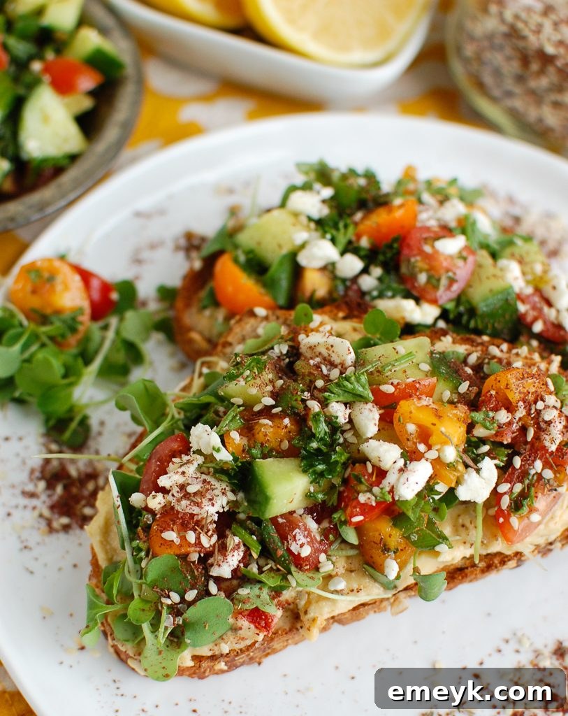 A beautifully arranged Mediterranean Hummus Toast with Za'atar on a white plate, ready to be enjoyed.