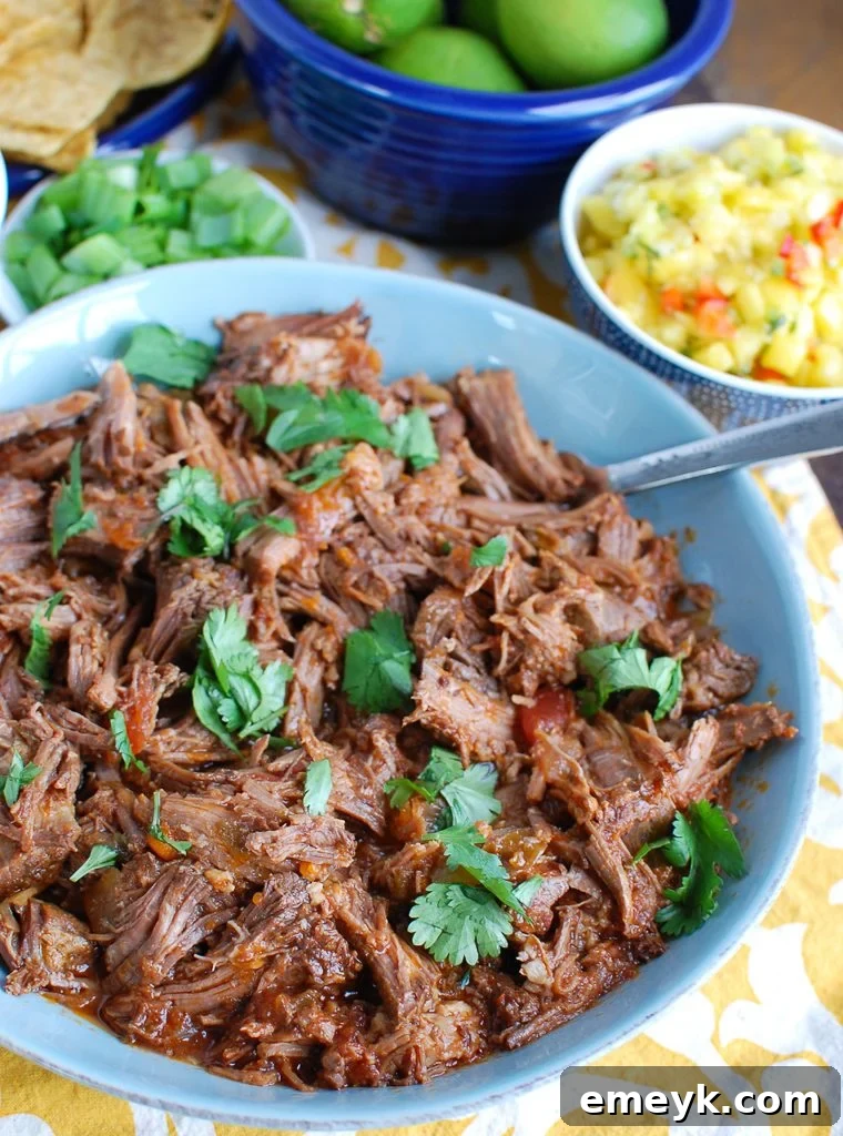 Scooping Beef Nachos with a spoon, showing the layers of ingredients