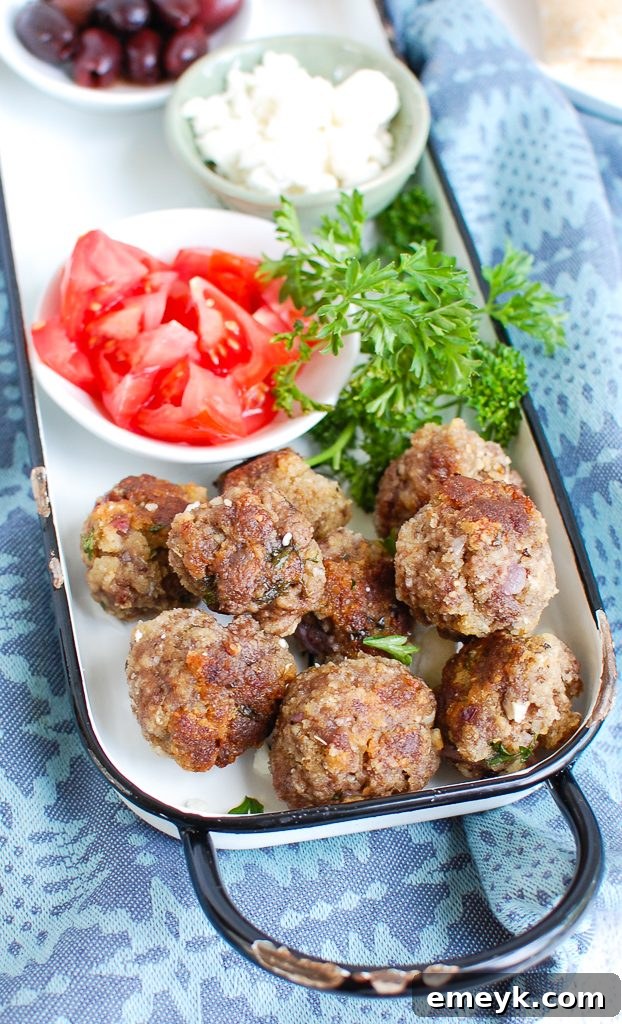 Uncooked Greek Meatballs arranged on a baking tray, ready for the oven.