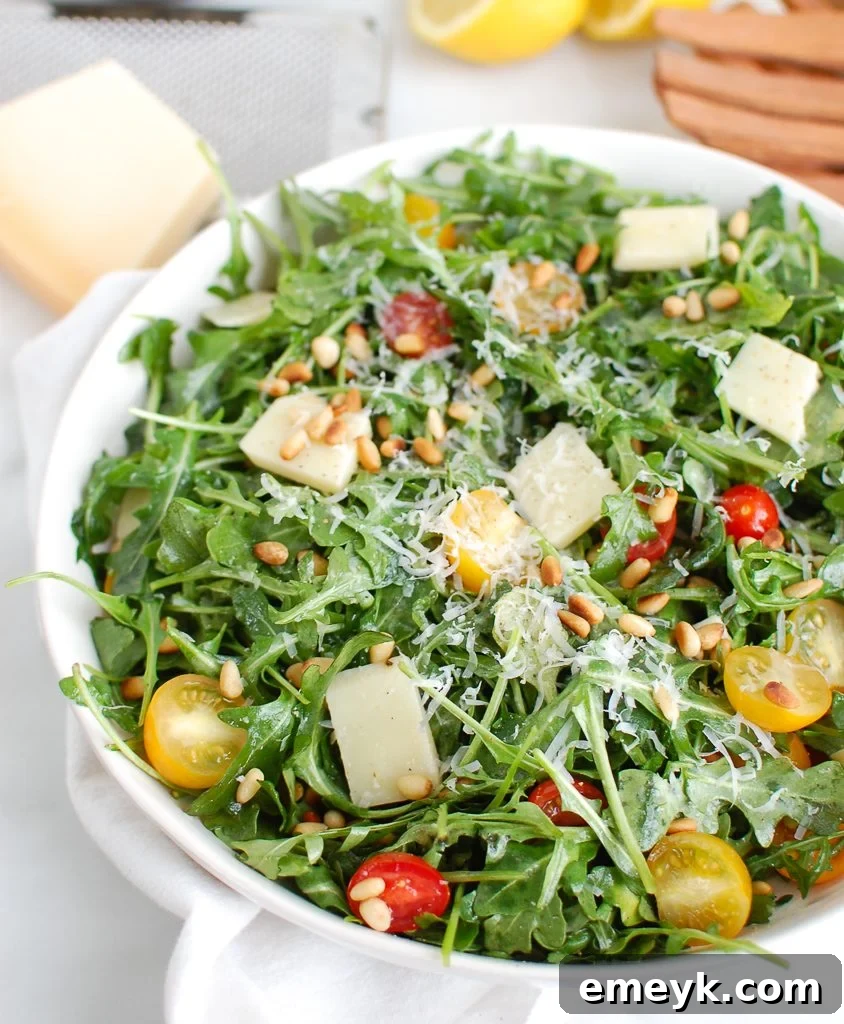 Serving Lemon Arugula Salad with Pine Nuts using wood tongs.