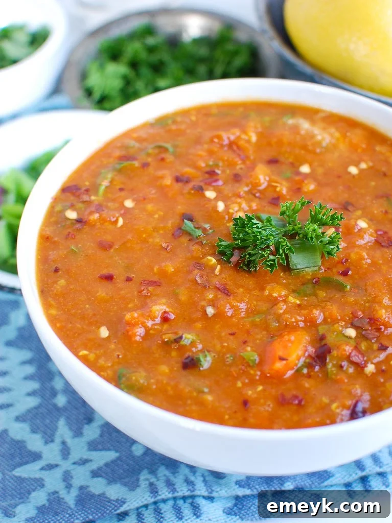 A steaming bowl of Slow Cooker Lentil Soup in a white bowl, garnished with fresh herbs.