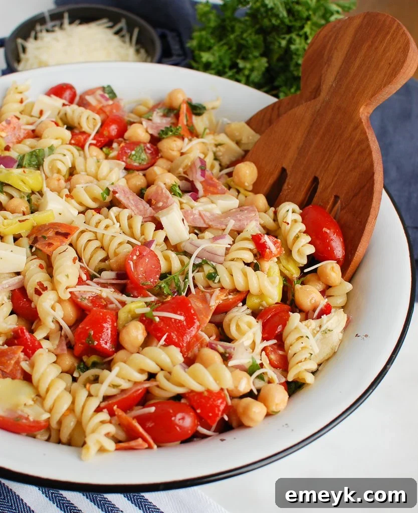 Vibrant Italian Pasta Salad served in a white ceramic bowl, garnished with fresh basil leaves, ready for a summer picnic or potluck